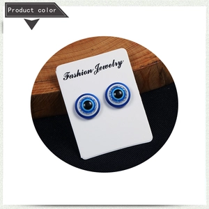 Detail of blue evil eye magnetic earrings with silver glitter on a display card