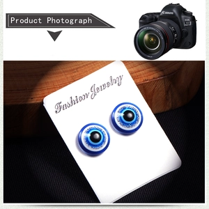 Detailed macro view of magnetic evil eye stud earrings with blue glitter accents