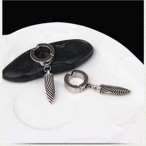 Macro detail of silver bullet pendant earrings with spiral texture on black pebbles