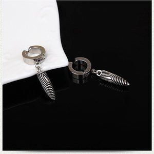 Detail of bullet-shaped non-piercing ear clips with spiral textures on a ceramic plate