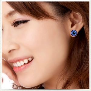 Close-up of a blue Evil Eye magnetic stud earring worn on a model's earlobe