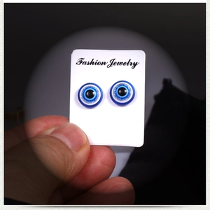 Macro shot of blue Evil Eye magnetic earrings with glitter detailing on display card