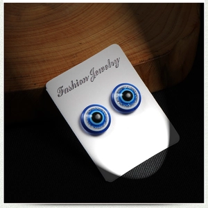 Evil Eye magnetic stud earrings with blue glitter design on wooden display background