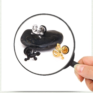 Dettaglio dei chiodini per orecchie a forma di geco in titanio nei colori argento, oro e nero