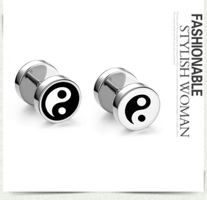 Macro detail of stainless steel barbell earrings featuring black and white Yin Yang design