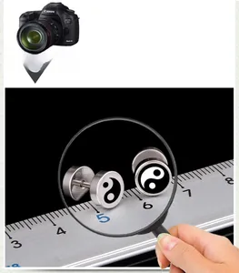 Macro detail of stainless steel barbell earrings featuring black and white Tai Chi Yin Yang design