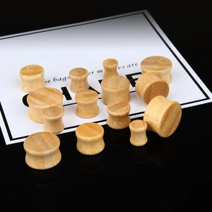 Natural bamboo wood ear gauges set with saddle plug design on black surface