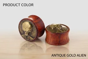 Macro shot of antique gold alien relief on dark red wood ear plugs with retro texture