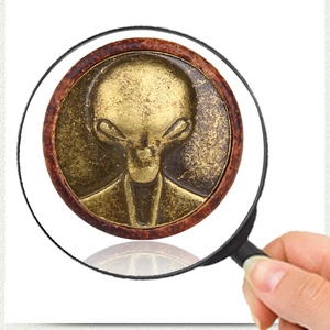 Macro view of vintage bronze alien head engraving on a textured round metal stud earring