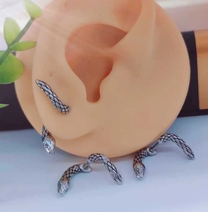 Macro shot of silver snake earrings featuring detailed scale texture on a silicone ear model
