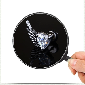 Close-up of wing-shaped stud earring with heart zircon stone and fine metal texture