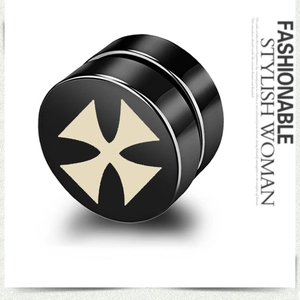 Vue macro d'un clip d'oreille magnétique noir avec motif de croix blanche et fini poli