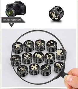 Detail of black magnetic stud earrings with laser engraved skull and star patterns
