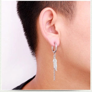 Détail d'une boucle d'oreille en titane argenté avec plume et chaîne portée à l'oreille