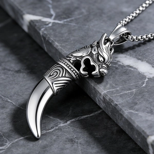Gros plan du pendentif tête de loup-dragon en acier inoxydable avec dent de loup tribal