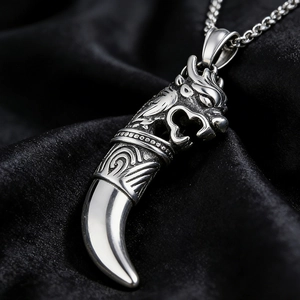 Vue macro d'un pendentif tête de dragon argenté et dent de loup sur velours noir