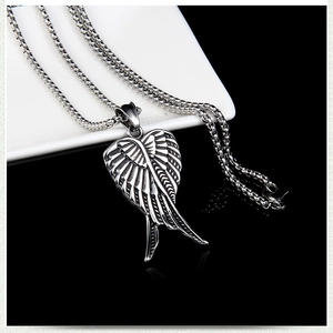 Détail macro du pendentif aile d'ange rétro en acier inoxydable et texture plume