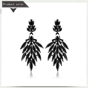 Macro detail of luxury black teardrop earrings with multi-layered crystal feather design