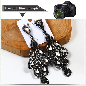 Close-up of black teardrop chandelier earrings with faceted rhinestones and vintage details