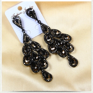 Macro detail of vintage black drop earrings with layered crystals on gold silk background