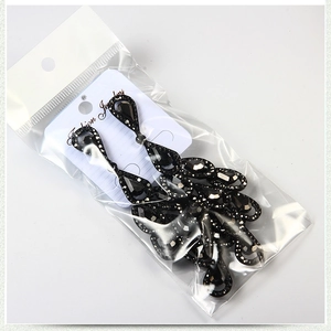 Macro detail of black teardrop earrings with crystal facets in retail packaging