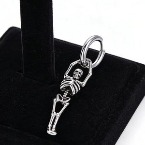 Gros plan d'une boucle d'oreille punk en acier inoxydable avec pendentif squelette
