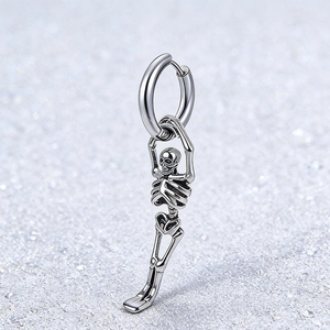 Vue rapprochée d'une boucle d'oreille squelette en acier sur fond gris scintillant