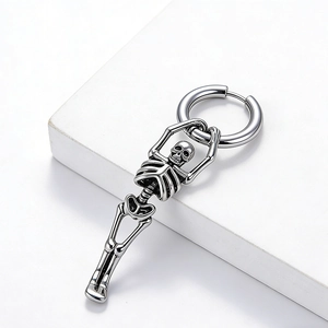 Détail d'un pendentif tête de mort style punk en acier inoxydable sur une créole polie