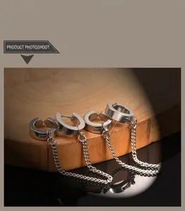 Detail of four silver punk ear cuffs with long metal chains on a wooden tray