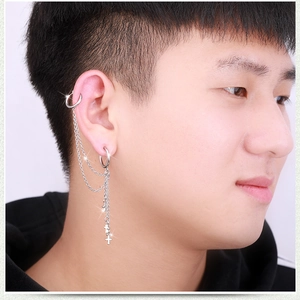 Detail of silver chain earrings with cross pendant in punk style on ear cartilage