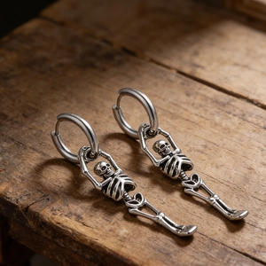 Détail de boucles d'oreilles squelette en argent vieilli sur un fond rustique en bois