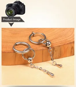 Close-up of stainless steel hoop earrings with chain and teardrop pendant on wood
