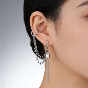 Close-up of silver steel ear cuff with double chains and geometric pendants on a model
