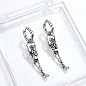 Détail des boucles d'oreilles squelette punk argentées sur un étui à bijoux clair