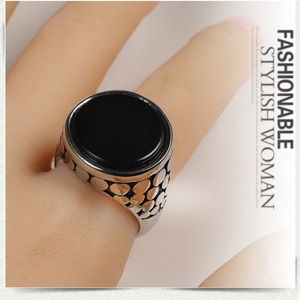 Macro view of vintage stainless steel ring with black gemstone and dotted texture band