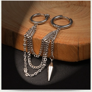 Detail of stainless steel hoop earrings with hanging tassel chains and a metal cone pendant