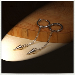 Detail view of steel tassel chain earrings with cone pendants on wood and fabric surface