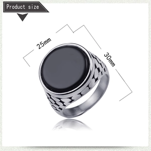 Detail view of men's silver steel ring with black gemstone and engraved geometric texture