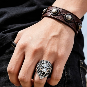 Detailed close-up of a silver lion head ring with a brown studded leather bracelet