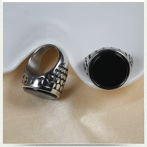Close-up of vintage men's ring with black stone and engraved dotted textures on steel
