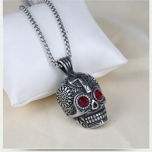 Detail of retro silver skull pendant with red gemstone eyes and floral carvings