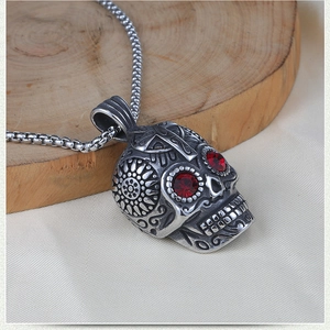 Close-up of vintage steel skull pendant with red rhinestone eyes and floral engravings