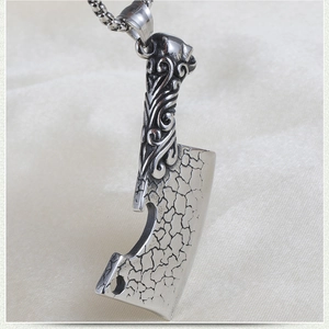 Macro shot of vintage steel butcher knife pendant with ornate carvings and bead chain