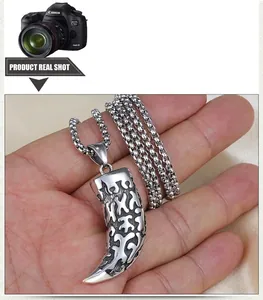 Detail of vintage wolf tooth pendant with tribal patterns on a steel chain necklace