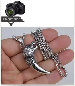Detail of hand-held wolf tooth pendant necklace in stainless steel with box chain