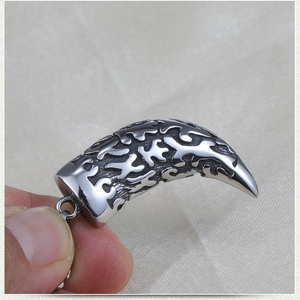 Macro shot of silver stainless steel wolf tooth pendant with intricate vintage carvings