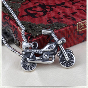 Detail view of retro silver motorcycle pendant with intricate carvings and steel chain