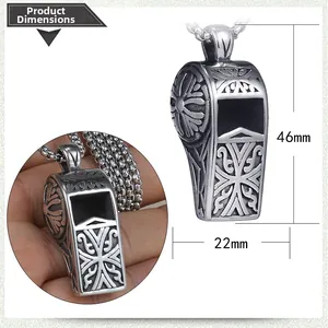 Detail view of a vintage stainless steel whistle pendant with ornate embossed patterns