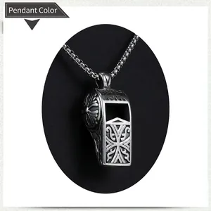Détail d'un pendentif sifflet en acier vintage avec gravures de vignes et croix ciselées