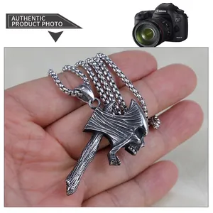 Detailed view of a vintage stainless steel skull axe pendant held in palm for scale